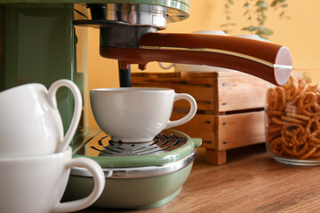 Modern coffee machine with cups on table, closeup