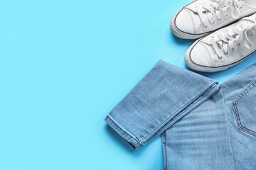 Stylish jeans with sneakers on blue background