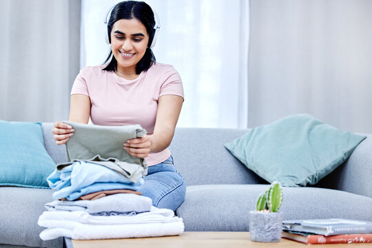 Have Fun With Your Chores. A Young Woman Folding Clothes At Home.