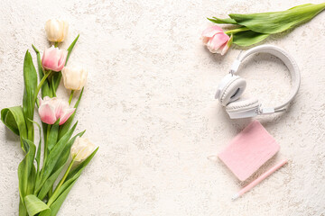 Obraz na płótnie Canvas Modern headphones, notebook and beautiful tulip flowers on light background