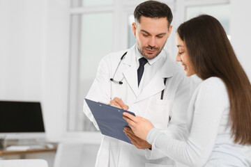 Doctor with clipboard consulting patient in clinic