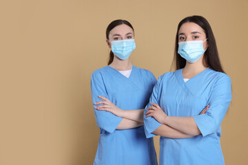 Nurses wearing protective masks on light brown background, space for text