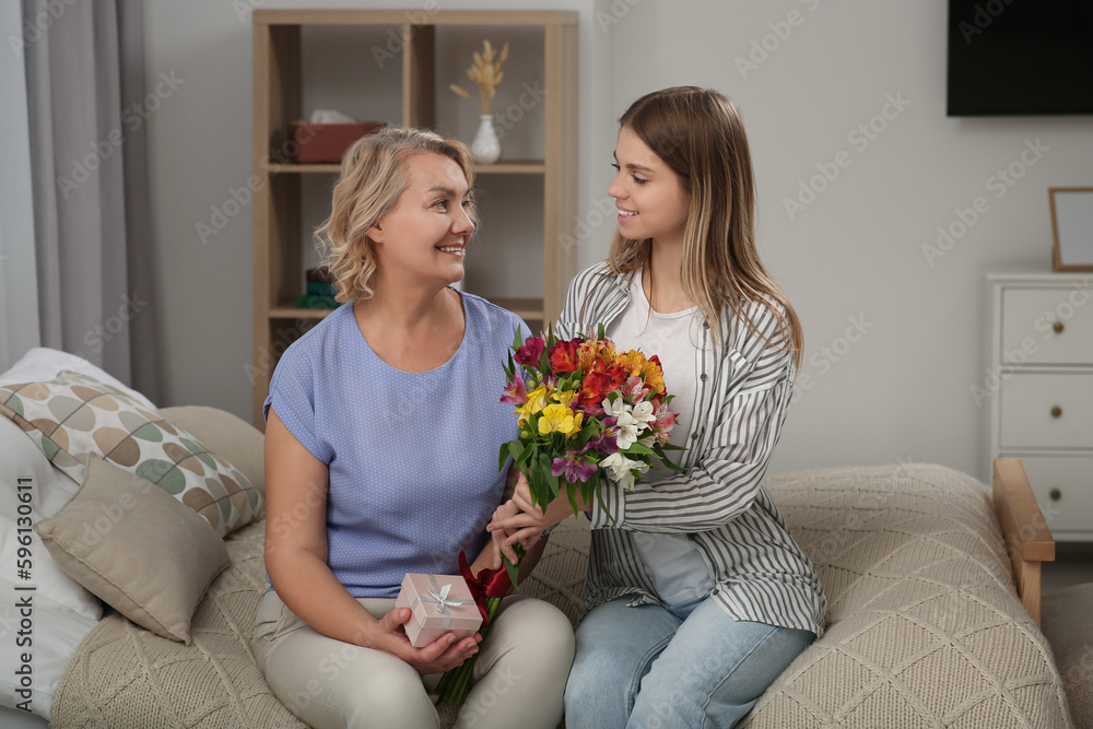 Sticker Young daughter congratulating her mom with flowers at home. Happy Mother's Day