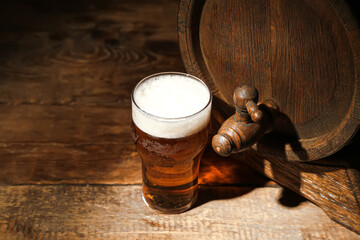 Oak barrel and glass of cold beer on wooden background