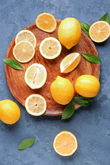 Wooden plate with fresh lemons on blue grunge background