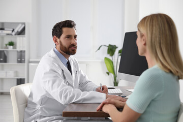 Doctor consulting patient at wooden table in clinic