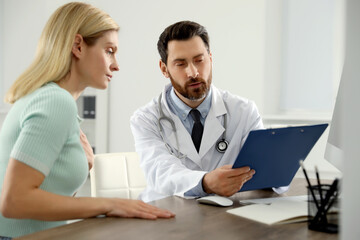 Doctor consulting patient at wooden table in clinic