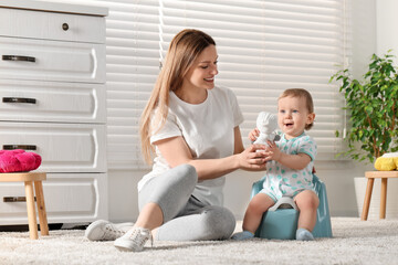 Mother training her child to sit on baby potty indoors