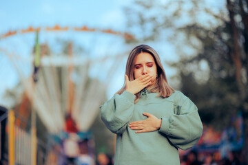 Woman Feels Like Throwing up after Ferris Wheel Ride. Dizzy girl feeling nauseated by motion...