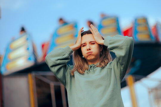 Stressed Woman Having her Head Spinning from Ferris Wheel. Fearful girl having headaches and panic attach at funfair 
