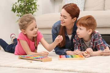 Happy mother and children playing with different math game kits on floor in room. Study mathematics...