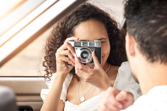May love and happiness follow you wherever you go in life. a young woman taking a picture of her boyfriend while sitting in a car together.