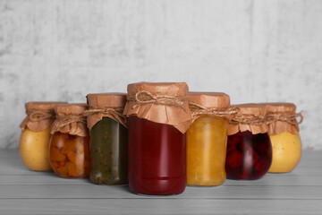 Jars with canned fruit jams on wooden table