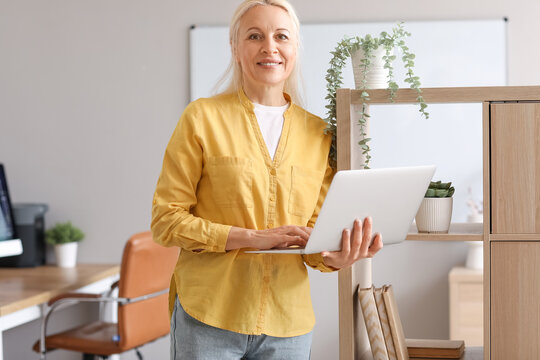 Mature female programmer working with laptop in office