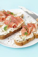 Plate of tasty bruschettas with jamon on blue background