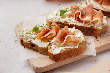 Wooden board of tasty bruschettas with jamon on white background