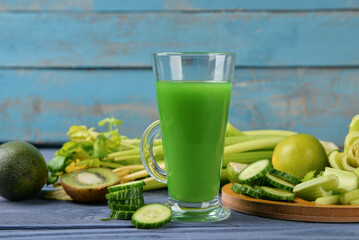 Glass of tasty green juice on blue wooden table