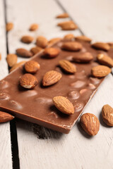 Sweet tasty chocolate with almonds on  light wooden background, closeup