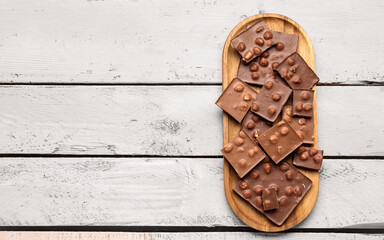 Plate with tasty chocolate with nuts on  light wooden background
