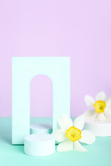 Decorative plaster podiums with flowers on turquoise table against violet background