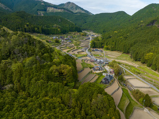 Aerial view of terraced fields and small farms in Japanese mountain village - 596141063