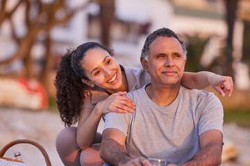 Its right over there. an attractive young woman sitting with her father and watching the sunset on the beach.