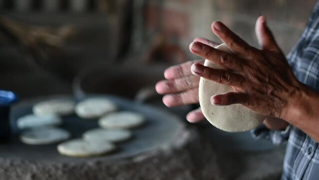 Mexican woman making a corn tortillas in a traditional way
