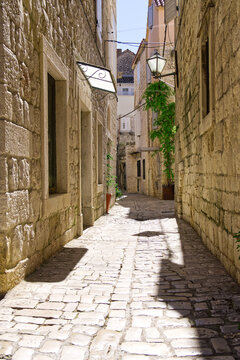 Fototapeta Narrow street with stone houses. Old houses and old narrow alley in Trogir, Croatia, Europe. Streets in old town.