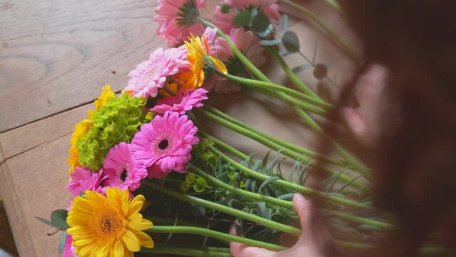 Flower arrangement of gerbera transvaal daisies close up from the florist over shoulder view in slow motion 4K
