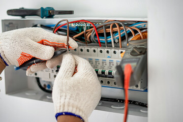 An electrical engineer is working on a home electrical control panel system and checking the...