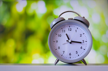 White alarm clock on a green background.