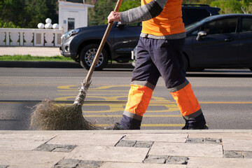 Close-up of a utility worker sweeping the street in the morning in the city.