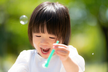 新緑の初夏の公園で遊ぶ笑顔の女の子