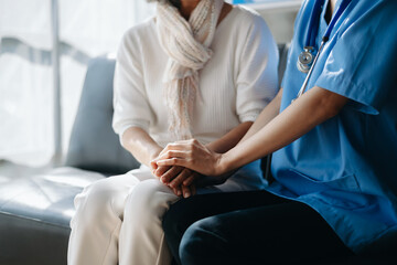 Fototapeta premium Medical doctor holing senior patient's hands and comforting her at home..