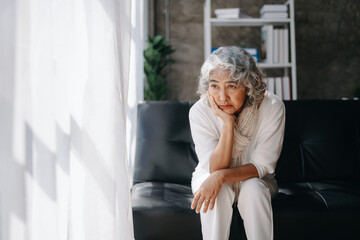 Old woman sit Depression haired  pensive glance Standing with bottle pills and pills by window  Copy space.