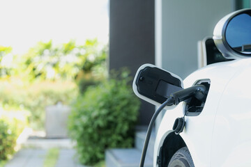 Closeup electric vehicle plugged-in with cable from charging point powered for progressive concept...