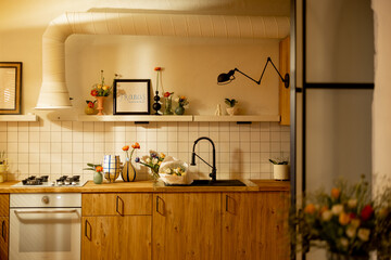 Modern kitchen interior made in natural materials with wooden facades and open shelves decorated with flowers. Home decorations and design concept