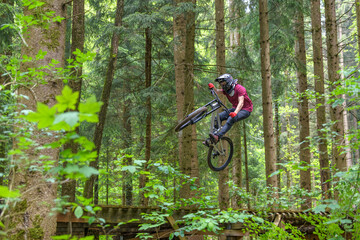 Fototapeta na wymiar Waghalsiger Freestyler springt mit seinem Mountainbike über eine Rampe im Bikepark