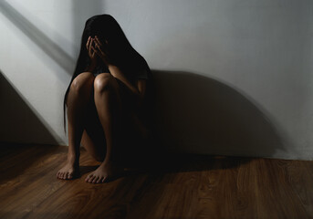 Silhouette low key dark shadow of young woman feeling sad upset or scared protecting from domestic...