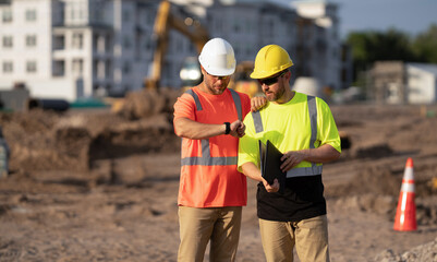 Construction foreman and civil engineer at work checking time schedule