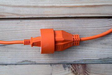 Orange electric wire, cable or extension cord on wood texture background
