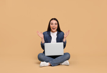 Naklejka premium Happy young woman with laptop on beige background