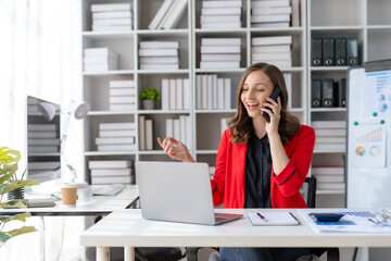 Obraz premium Beautiful smiling businesswoman talking on mobile phone while working in office.