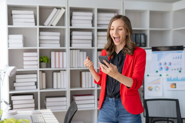 Happy businesswoman raising hands with victory smiling happily with smart phone. The concept of success at work.