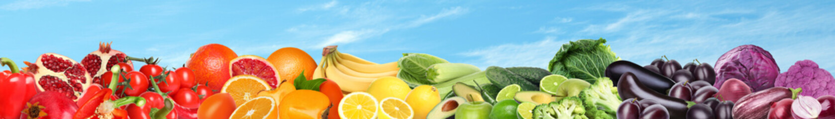 Many different fresh fruits and vegetables against blue sky with clouds. Banner design