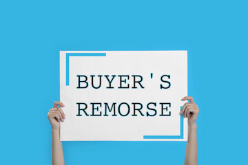 Woman holding poster with text Buyer's Remorse on light blue background, closeup