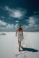 Summer woman in hat walking away in white sand , blue sky. Ai generative
