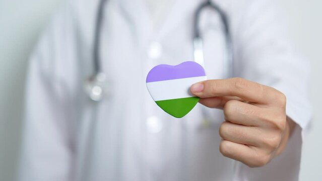 Queer Pride Day and LGBT pride month concept. Doctor hand holding purple, white and green heart shape with Stethoscope for Lesbian, Gay, Bisexual, Transgender, genderqueer and Pansexual community