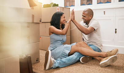 Happy couple, high five and moving in new home for real estate purchase, property or homeowner. Woman and man touching hands in happiness on floor for mortgage loan, finance or relocation with boxes