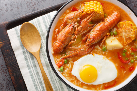 Thick chowder with crayfish, tomatoes, corn, pepper, potato, green peas and egg close-up in a bowl on the table. Horizontal top view from above